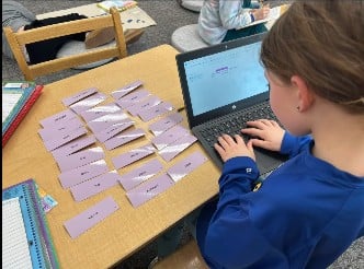 Montessori student typing the words they see on the table.