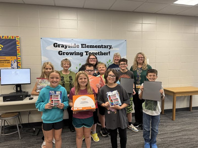 Students and adults stand in a hallway with school supplies.