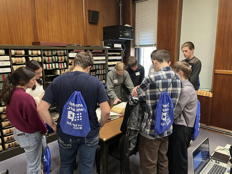 Students examine historical records and documents at a Juneau County event.
