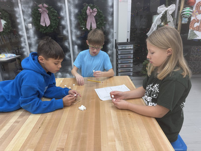 Students building structures with marshmallows and toothpicks during a classroom activity.