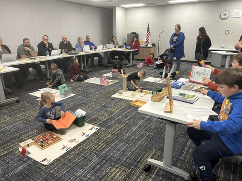 Students and staff participating in a Montessori-style educational demonstration during a meeting.