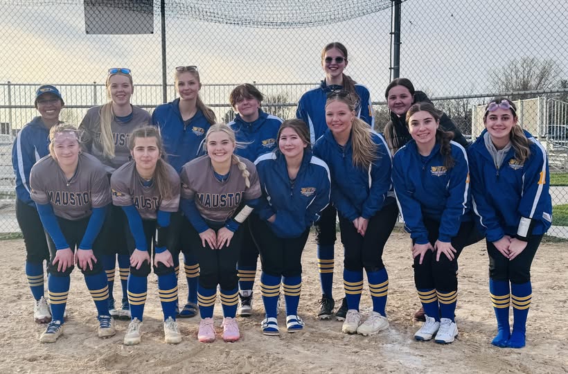 A group of girls in blue and gold softball uniforms posing together on a dirt infield.